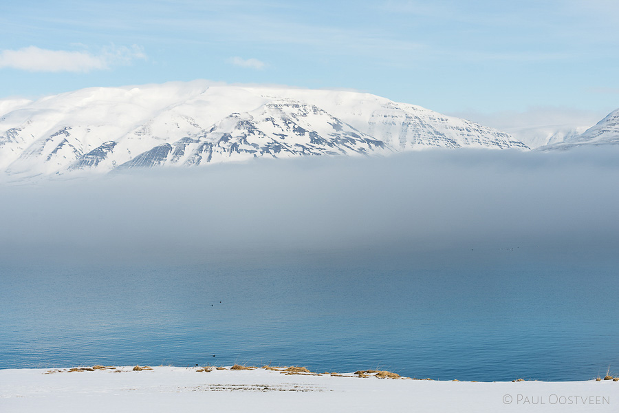 Eyjafjördur fjord in de winter. Met sneeuw bedekte bergen boven laaghangende wolken.